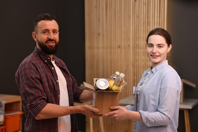 Photo of Volunteers holding donation box with food products indoors