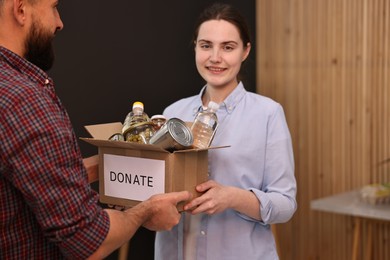 Photo of Volunteers holding donation box with food products indoors