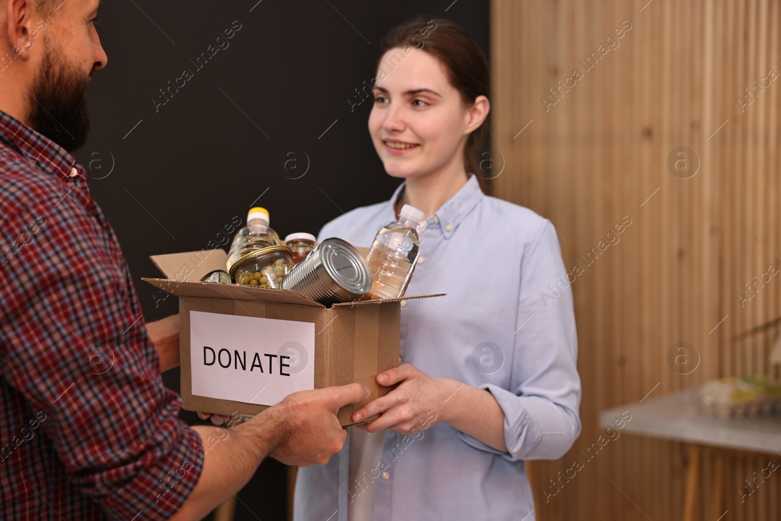 Photo of Volunteers holding donation box with food products indoors