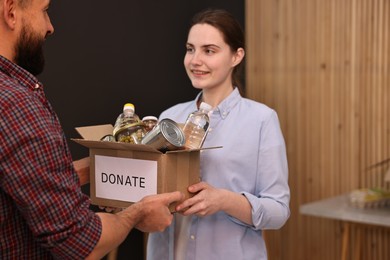 Photo of Volunteers holding donation box with food products indoors