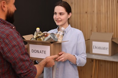 Photo of Volunteers holding donation box with food products indoors