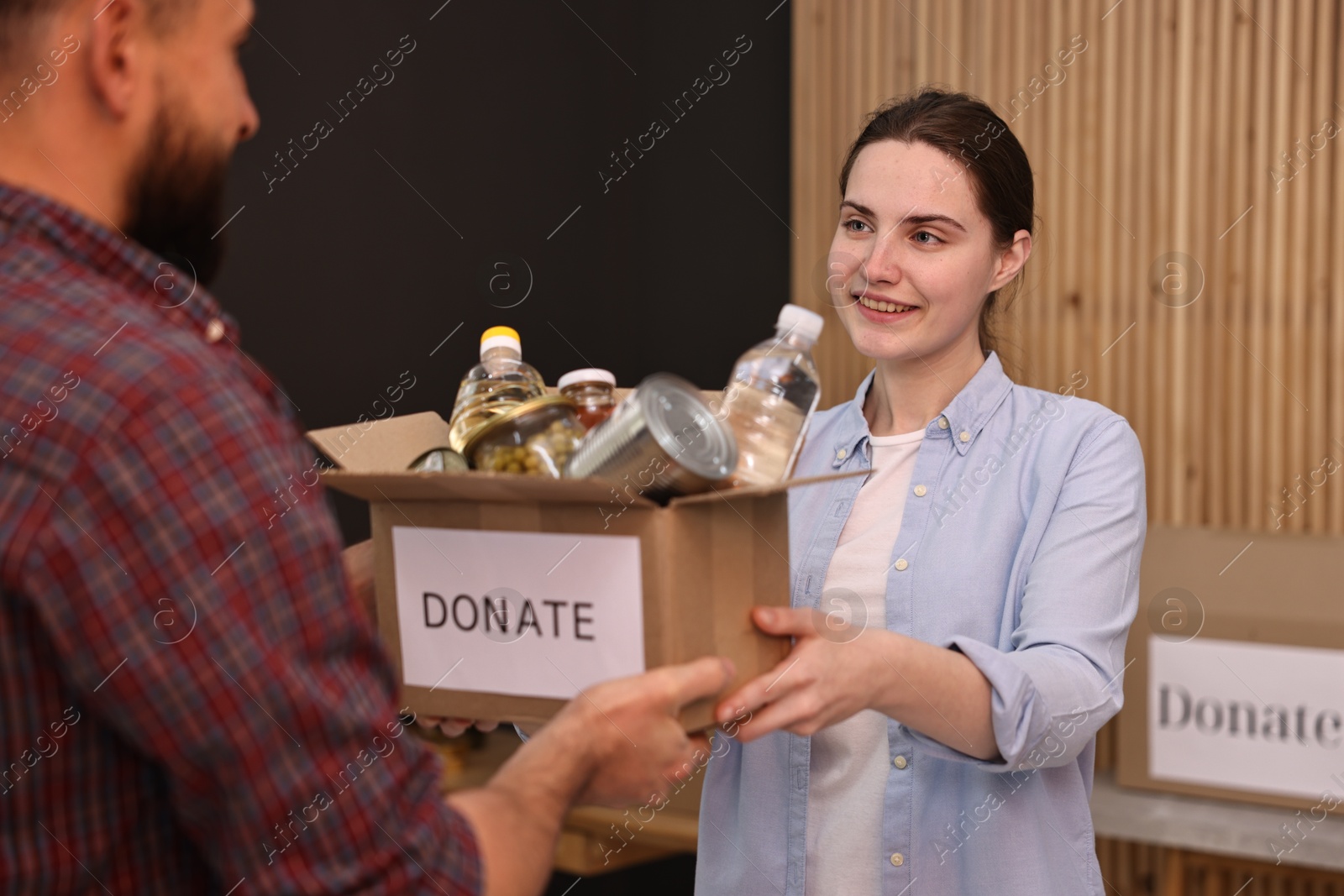 Photo of Volunteers holding donation box with food products indoors