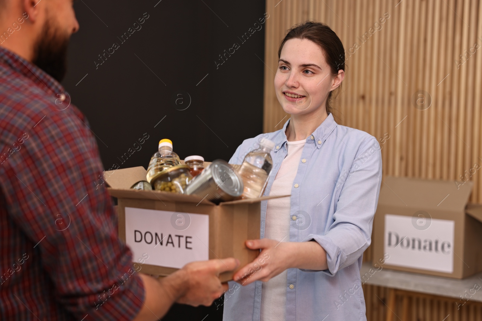 Photo of Volunteers holding donation box with food products indoors