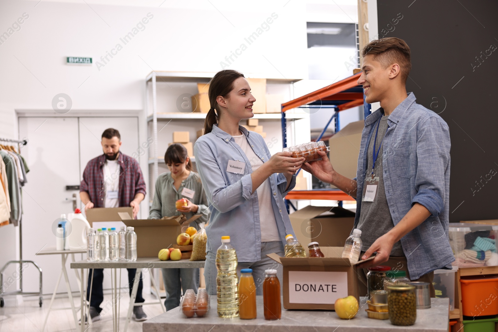 Photo of Volunteers packing food donations at tables indoors, selective focus