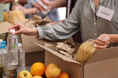 Volunteers packing food donations at table indoors, closeup