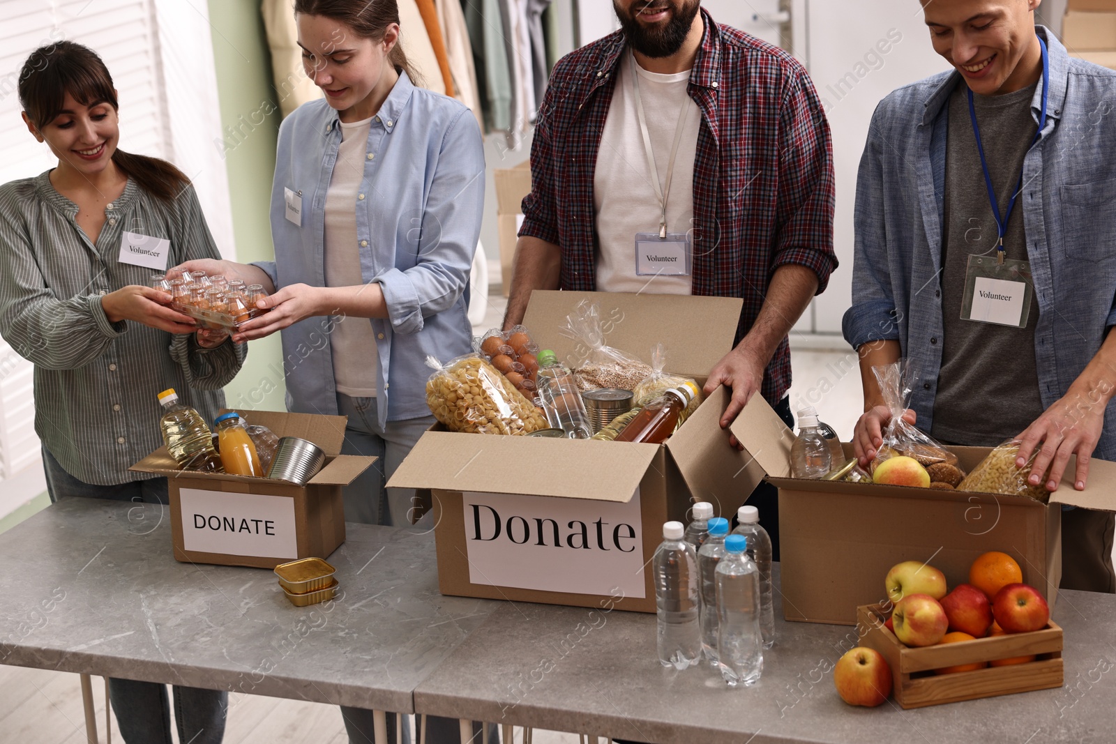 Photo of Group of volunteers packing food donations at table indoors