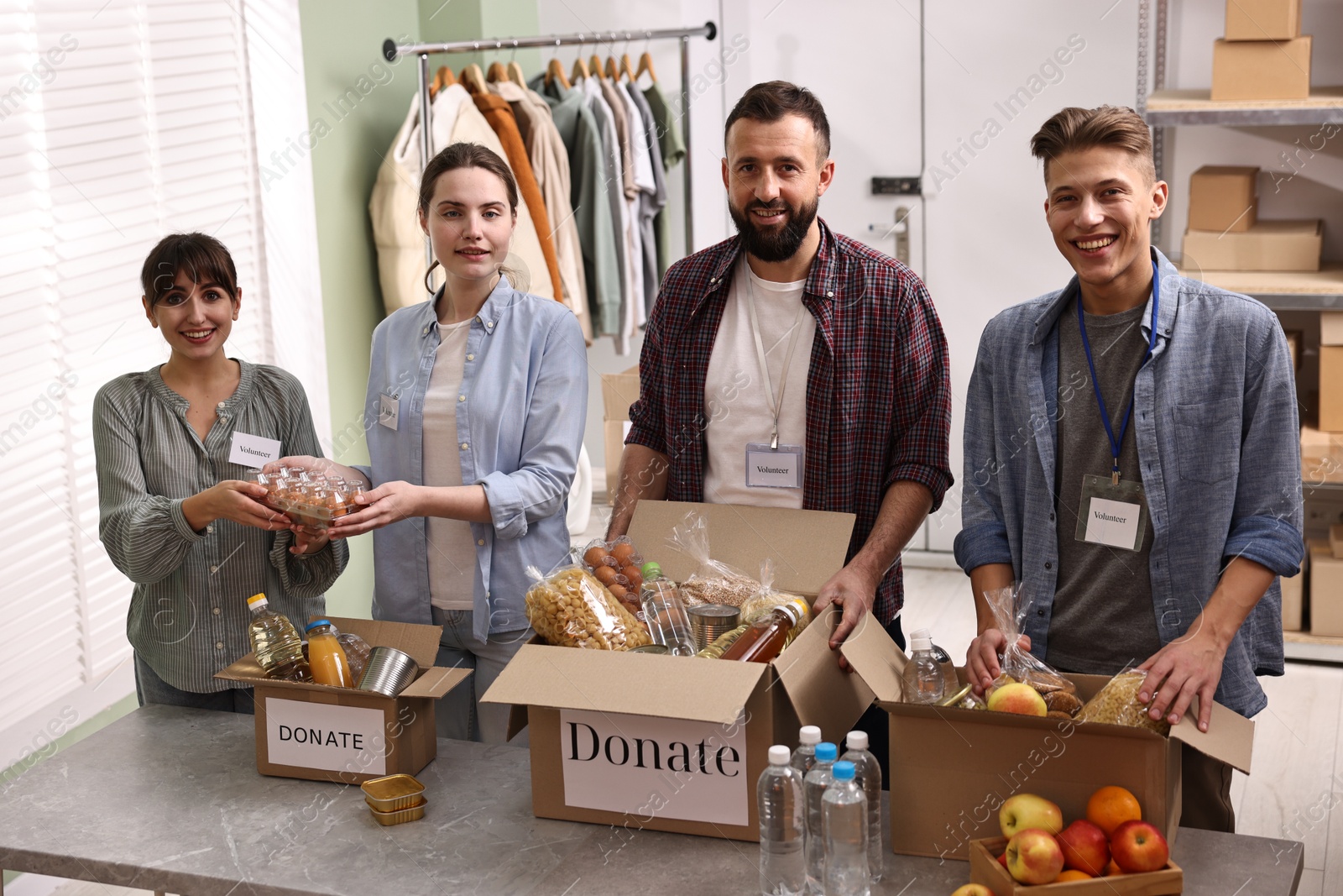 Photo of Group of volunteers packing food donations at table indoors