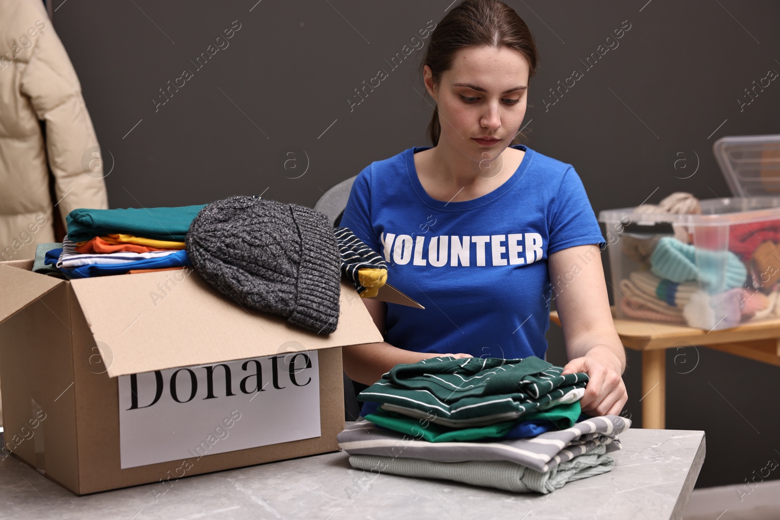 Photo of Volunteer sorting clothes for donation at table indoors