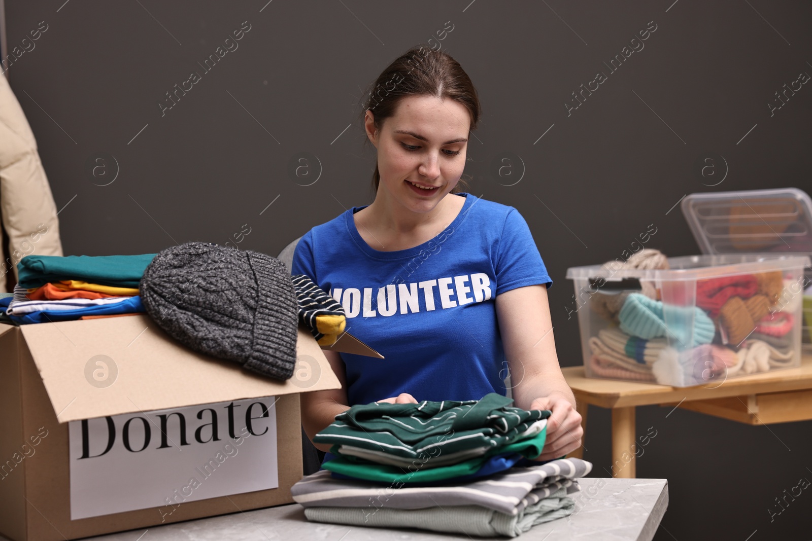 Photo of Volunteer sorting clothes for donation at table indoors