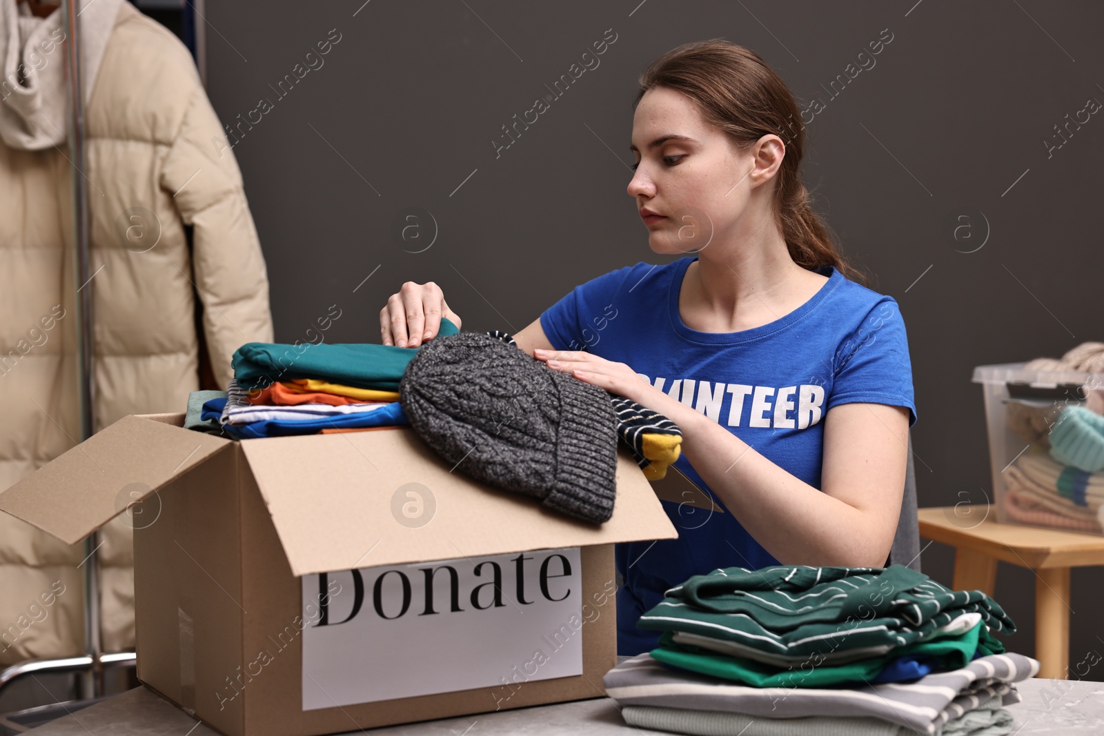 Photo of Volunteer putting clothes into donation box at table indoors