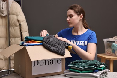 Photo of Volunteer putting clothes into donation box at table indoors