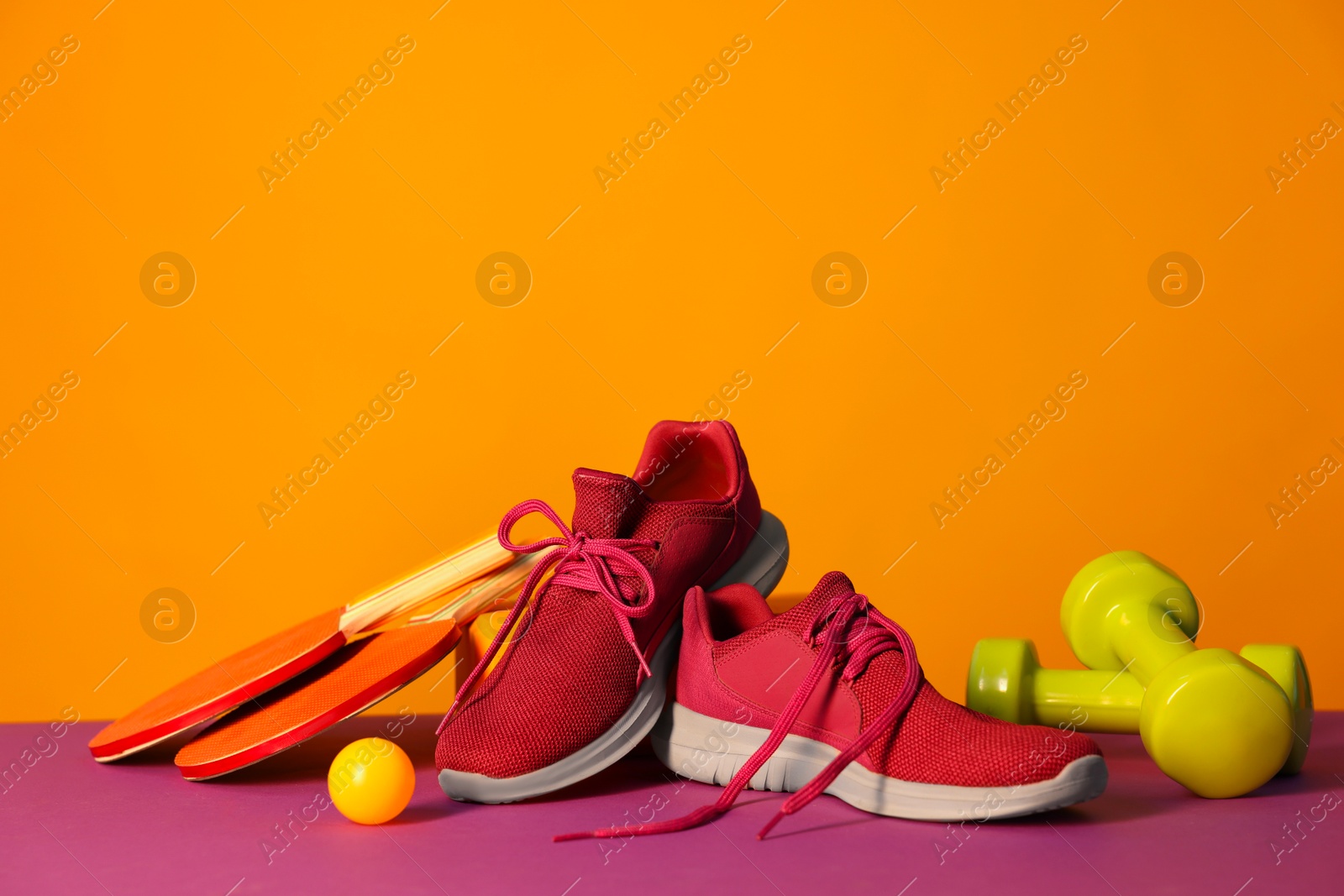 Photo of Stylish sneakers and different sports equipment on color background