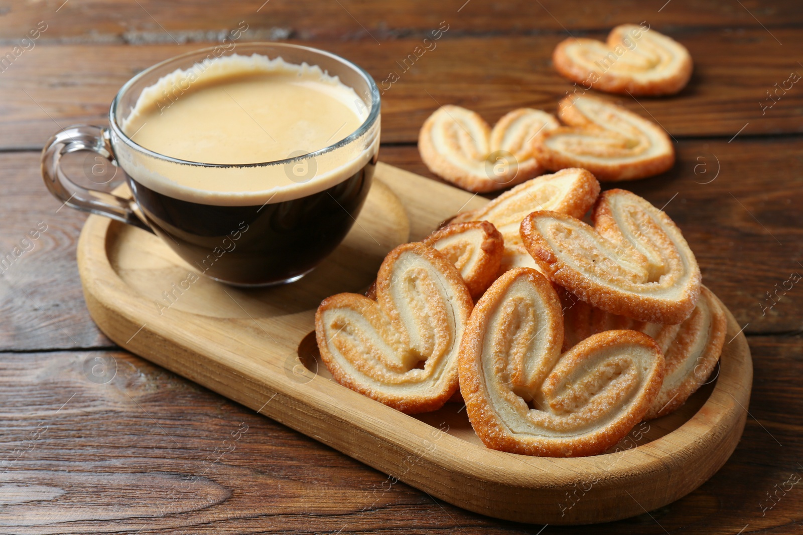 Photo of Tasty french palmier cookies and coffee on wooden table, closeup