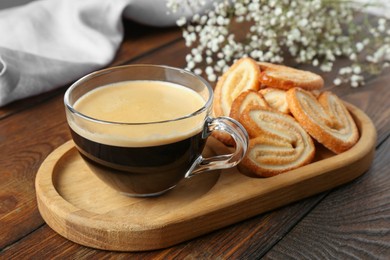 Photo of Tasty french palmier cookies and coffee on wooden table, closeup