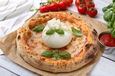 Photo of Delicious pizza with burrata cheese, basil, sauce and tomatoes on wooden table, closeup