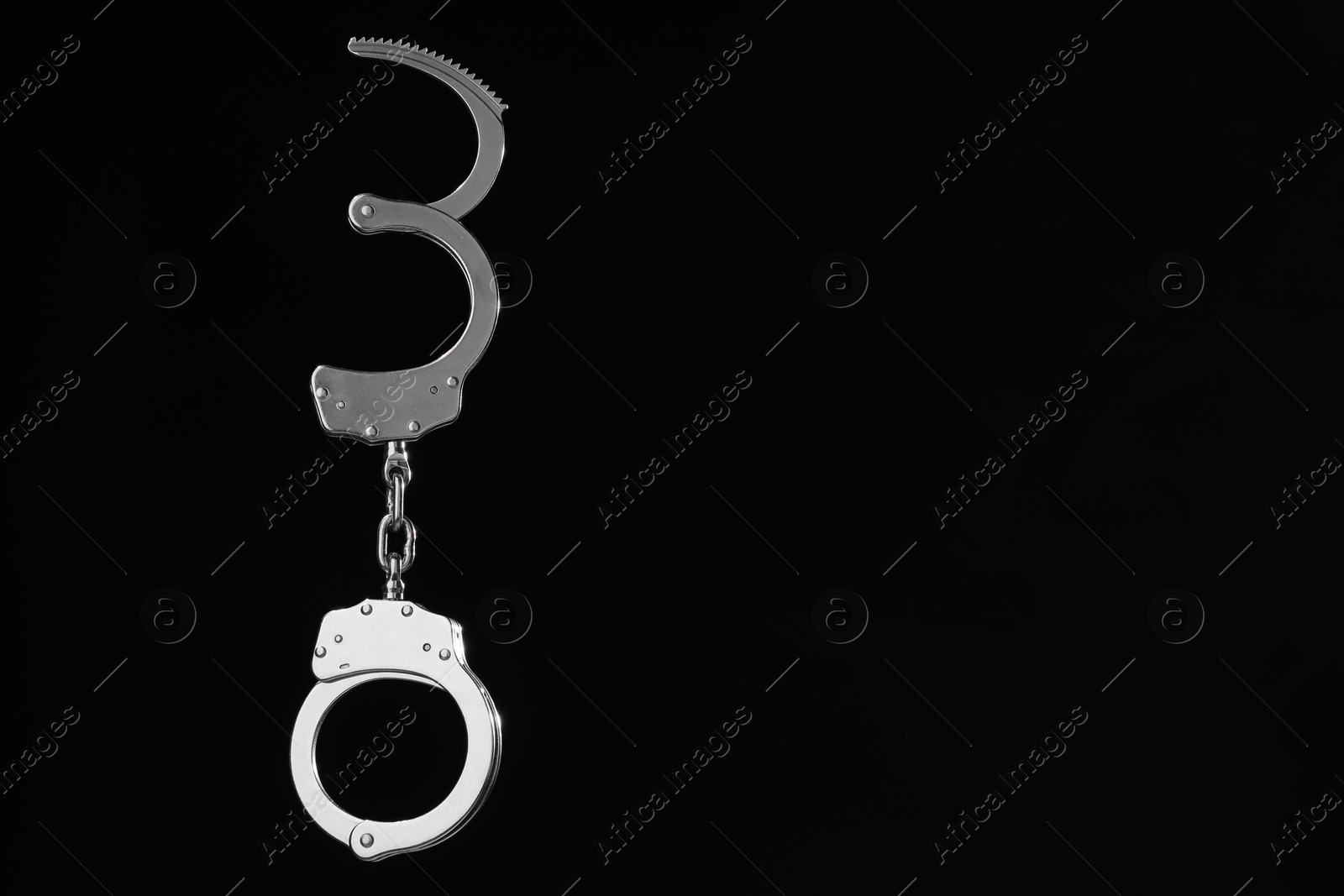 Photo of Metal chain handcuffs on black background. Space for text