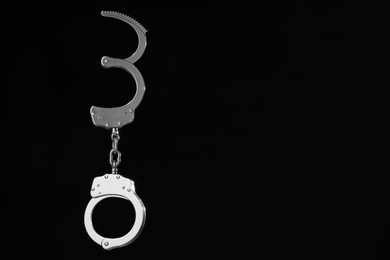 Photo of Metal chain handcuffs on black background. Space for text