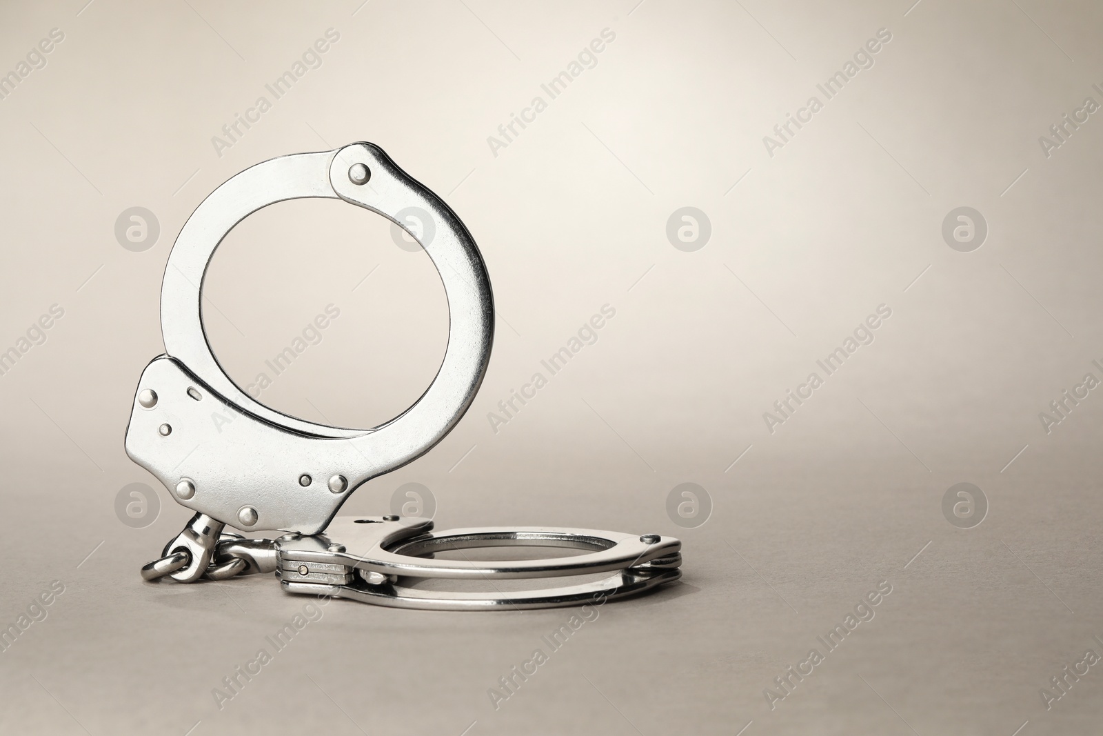 Photo of Metal chain handcuffs on light grey background, closeup. Space for text