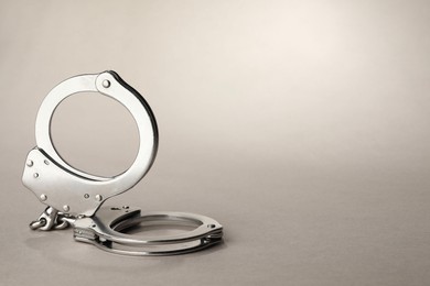 Photo of Metal chain handcuffs on light grey background, closeup. Space for text