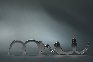 Photo of Metal chain handcuffs on grey background. Space for text