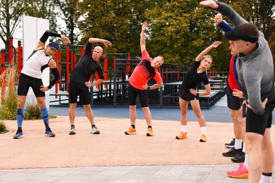 Photo of Group of people exercising and stretching outdoors