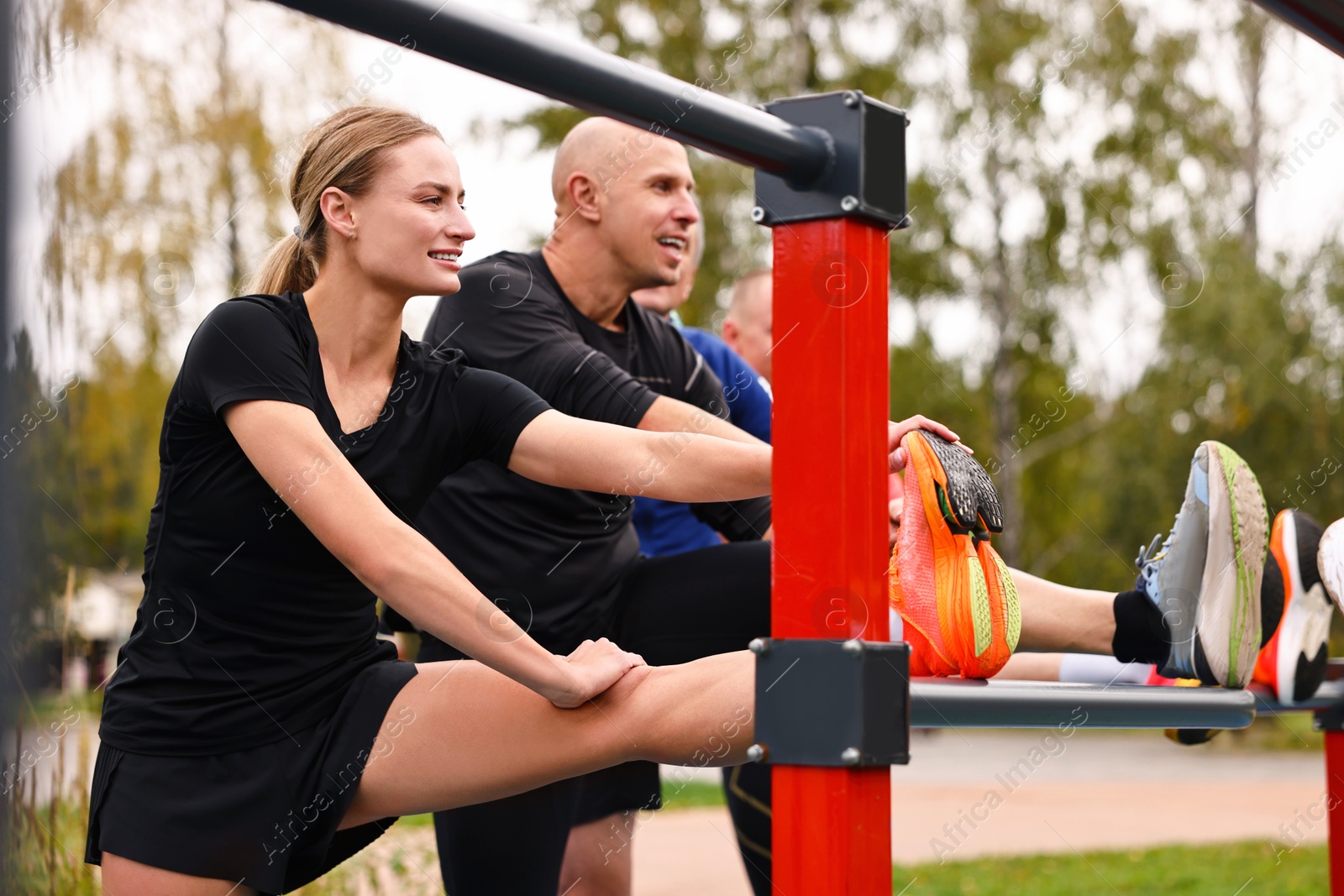 Photo of Group of people stretching near outdoor equipment in park. Healthy lifestyle