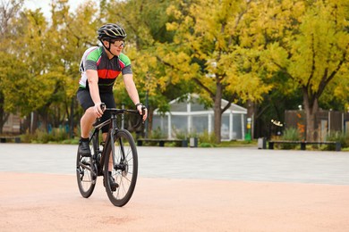 Photo of Athletic man with helmet riding bicycle outdoors, space for text