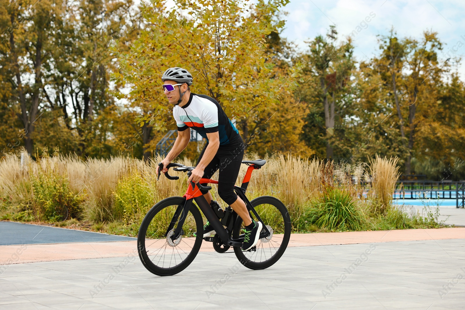 Photo of Athletic man with helmet riding bicycle outdoors