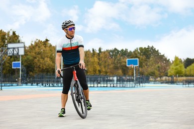 Photo of Athletic man with helmet and bicycle outdoors, space for text