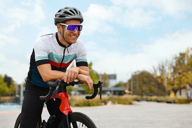 Photo of Athletic man with helmet and bicycle outdoors, space for text