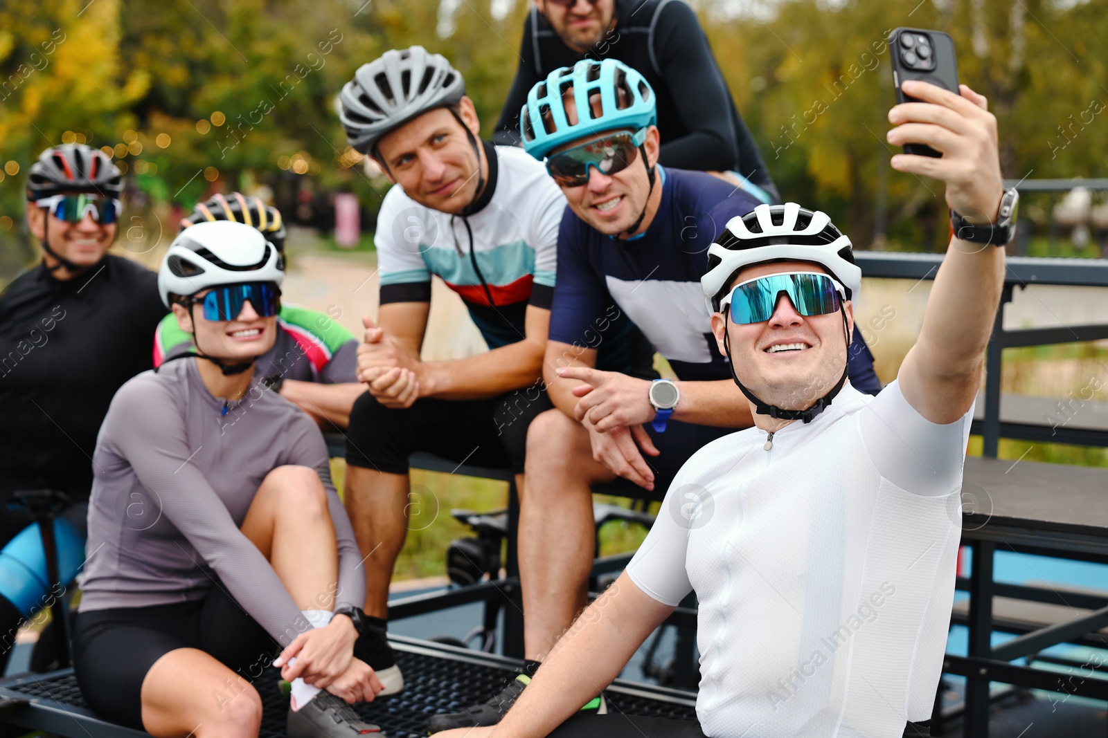 Photo of Group of athletic people with helmets and bicycles taking selfie outdoors