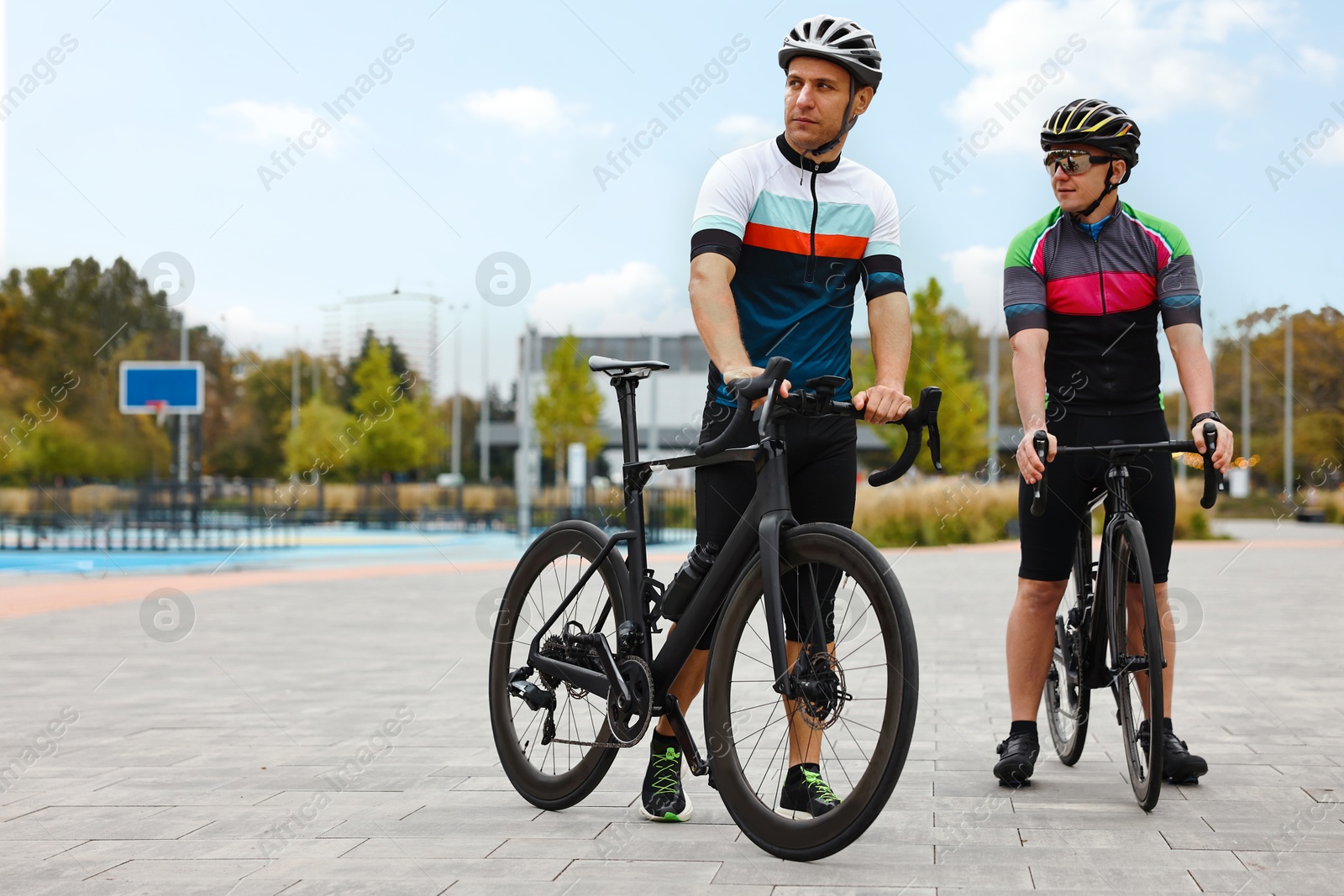 Photo of Athletic men with helmets and bicycles outdoors