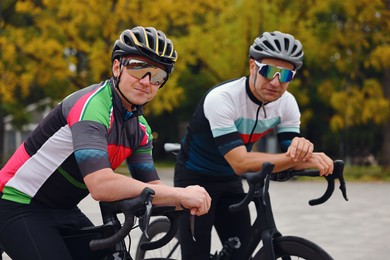 Photo of Athletic men with helmets and bicycles outdoors