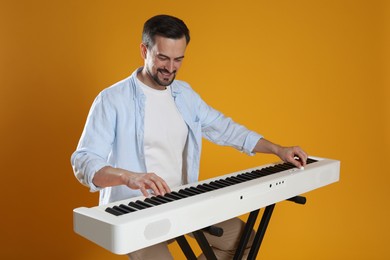 Photo of Bearded man playing synthesizer on orange background