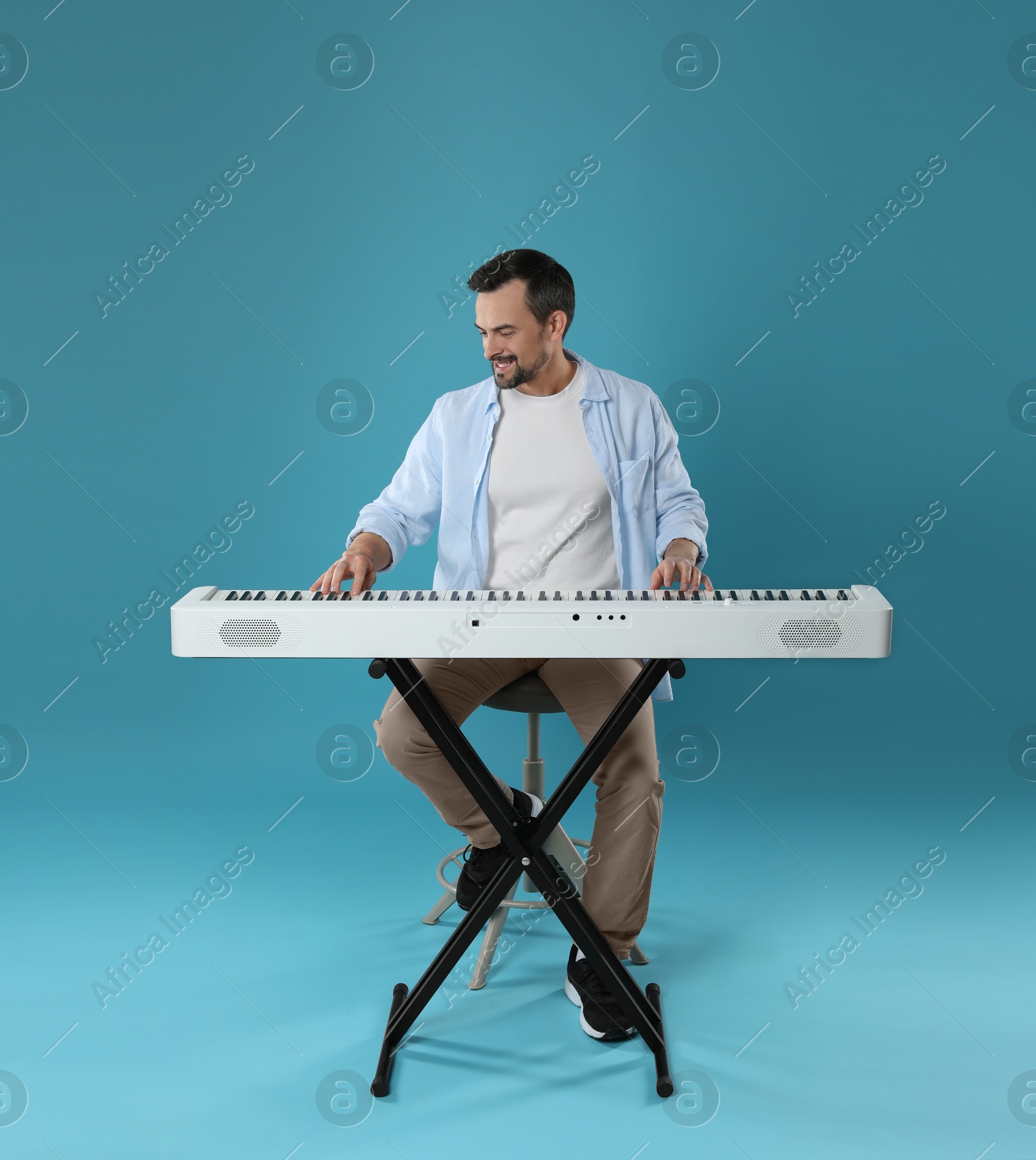 Photo of Man playing synthesizer on light blue background