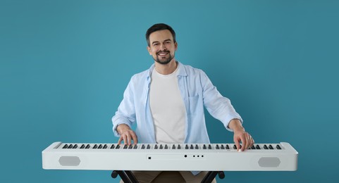 Photo of Smiling man playing synthesizer on light blue background