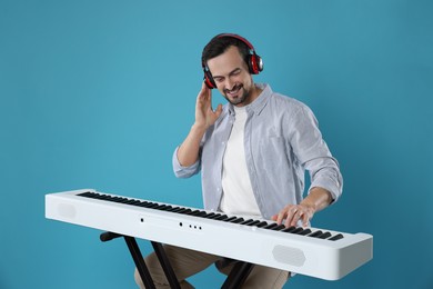 Photo of Smiling man playing synthesizer on light blue background