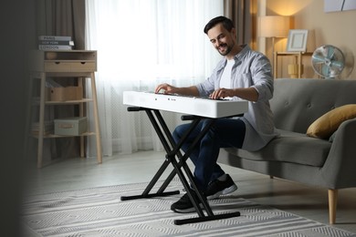 Photo of Smiling man playing synthesizer at home. Electronic musical instrument