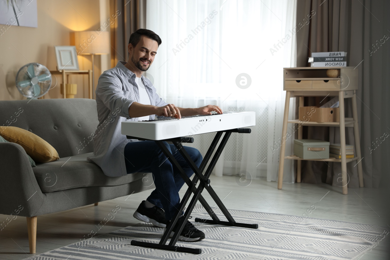 Photo of Smiling man playing synthesizer at home. Electronic musical instrument