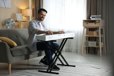 Photo of Smiling man playing synthesizer at home. Electronic musical instrument