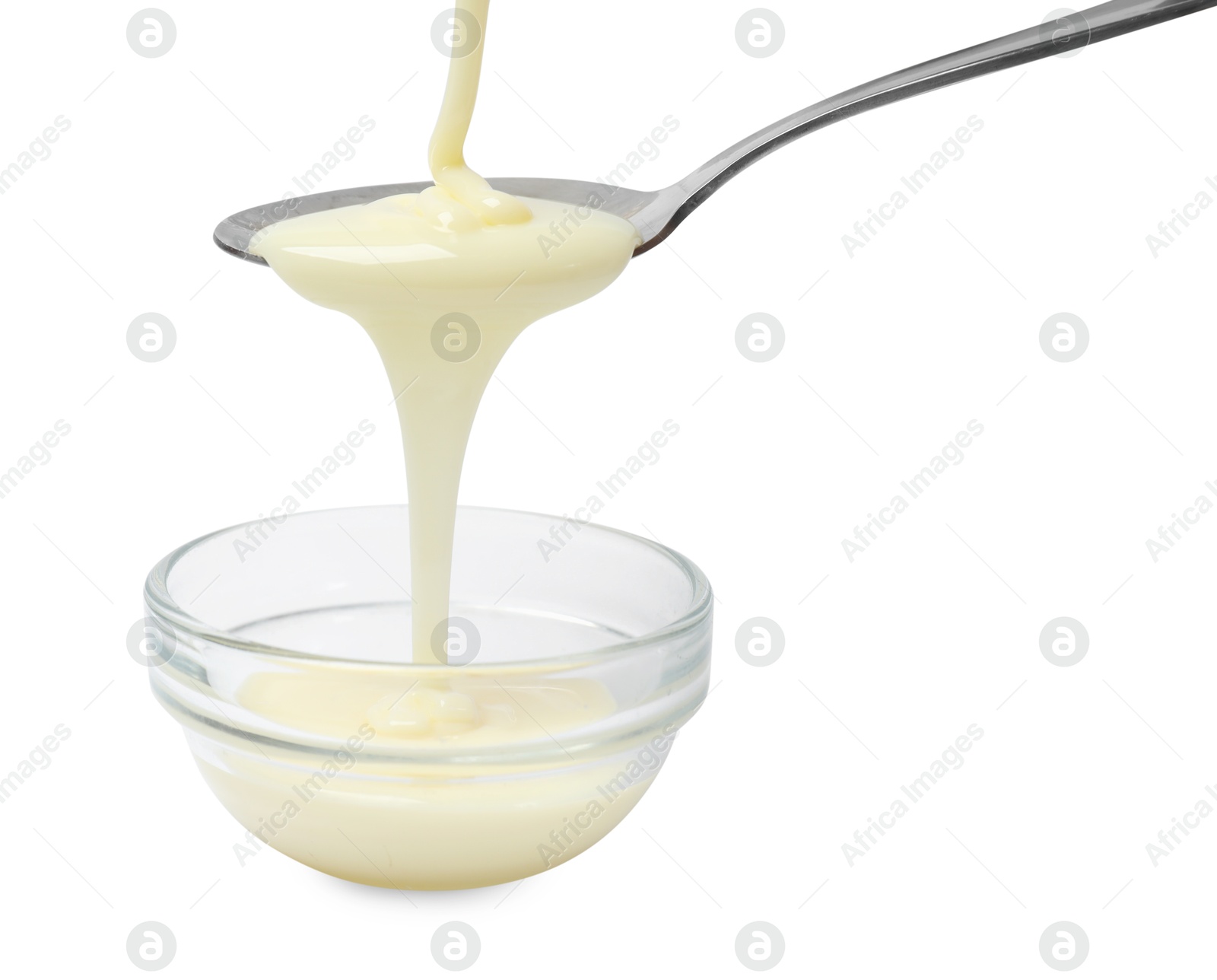 Photo of Condensed milk flowing down from spoon into bowl isolated on white