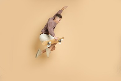 Photo of Handsome man jumping with skateboard on beige background. Space for text