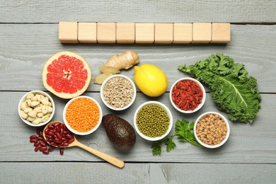 Photo of Superfood. Different healthy food products and cubes on grey wooden table, flat lay