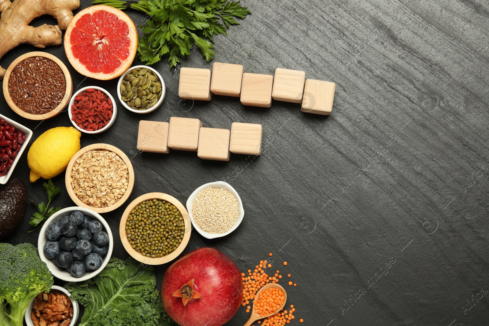 Photo of Superfood. Different healthy food products and blank wooden cubes on grey table, flat lay. Space for text