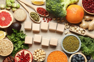 Photo of Different superfood products and blank cubes on wooden table, flat lay. Space for text