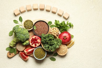 Photo of Different superfood products and blank cubes on light table, top view. Space for text