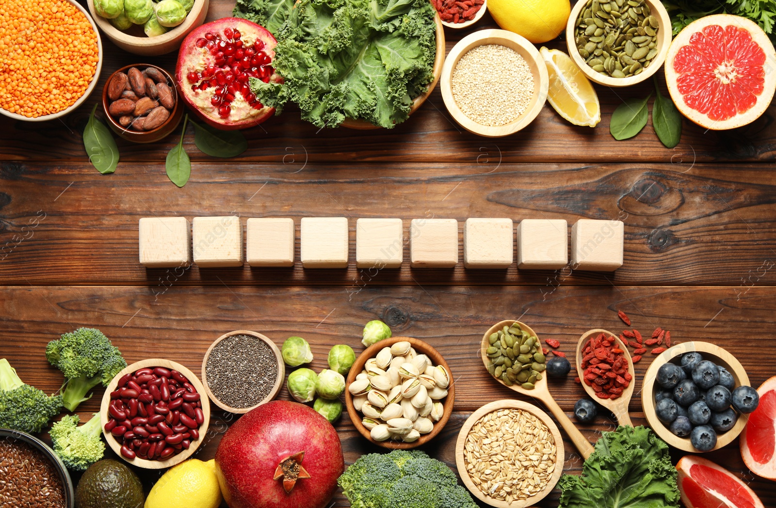 Photo of Different superfood products and blank cubes on wooden table, flat lay. Space for text