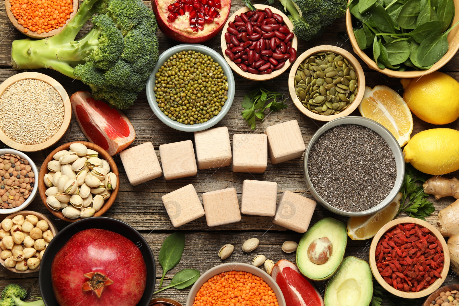 Photo of Different superfood products and blank cubes on wooden table, flat lay. Space for text