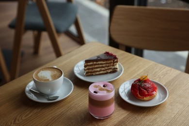 Photo of Aromatic coffee and delicious desserts served on wooden table in cafe