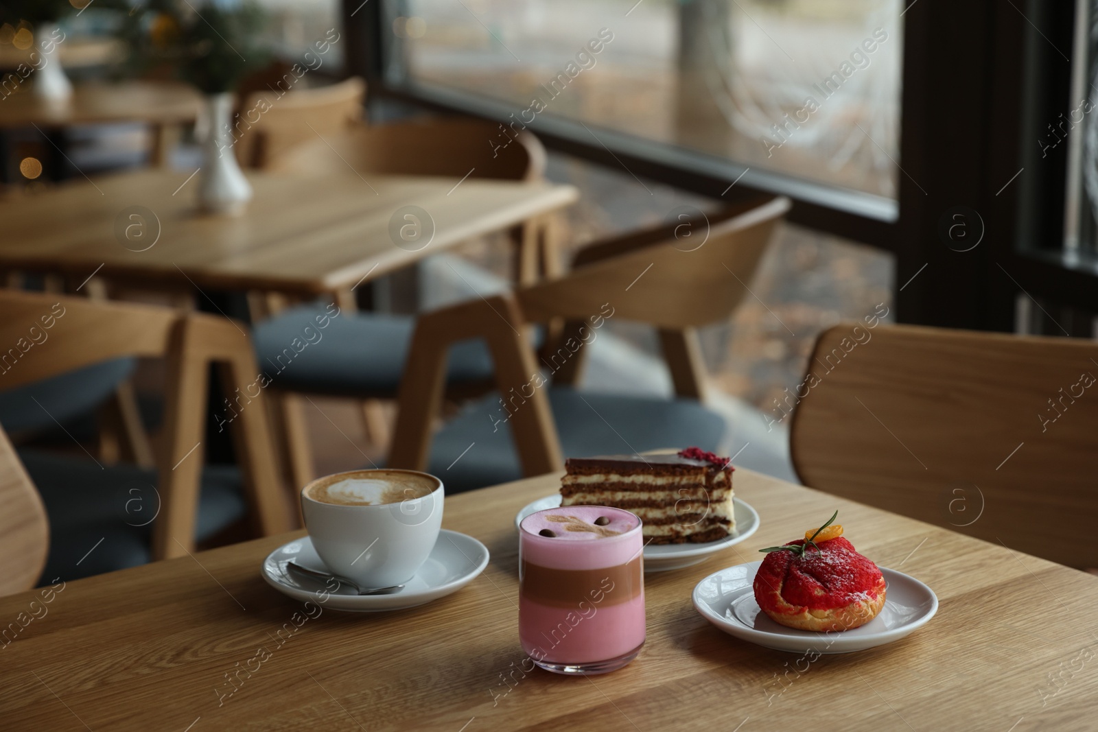 Photo of Aromatic coffee and delicious desserts served on wooden table in cafe